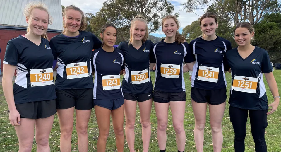Un gruppo di giovani atlete si trova nel campus della Hobart City High School davanti a uno sfondo alberato.