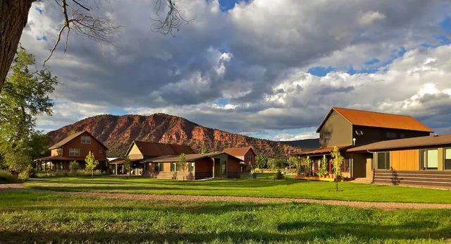 Lodge rustici su un prato verde con montagne sullo sfondo nel campus della Colorado Rocky Mountain School.