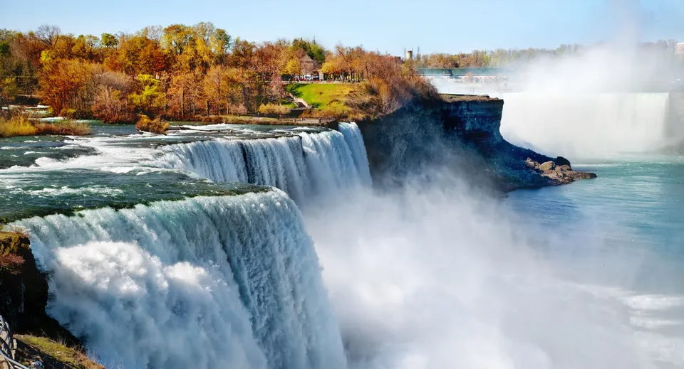 Una cascata scorre lungo un pendio roccioso davanti al fogliame autunnale nel terreno della F.P. Walshe School.