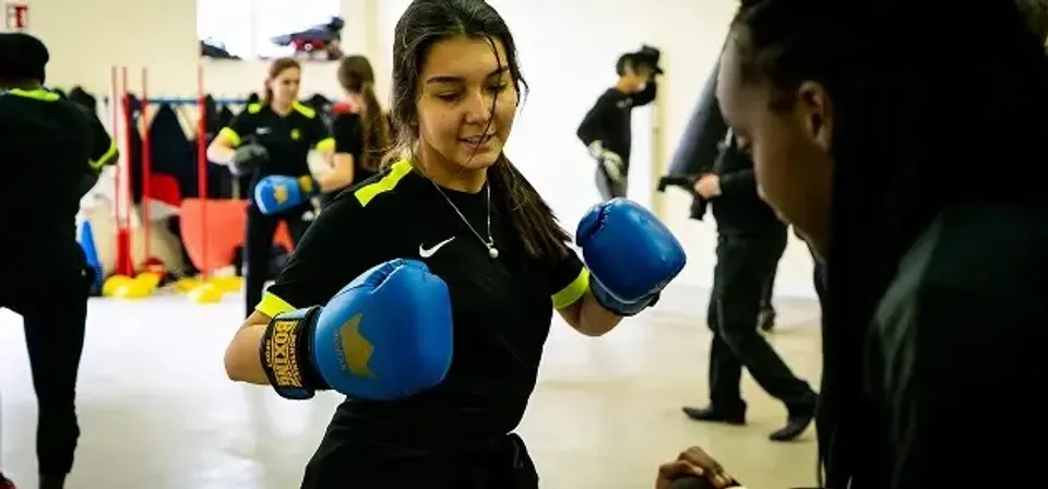 Una giovane donna con guanti da boxe si allena nella palestra della Ecole des roches.