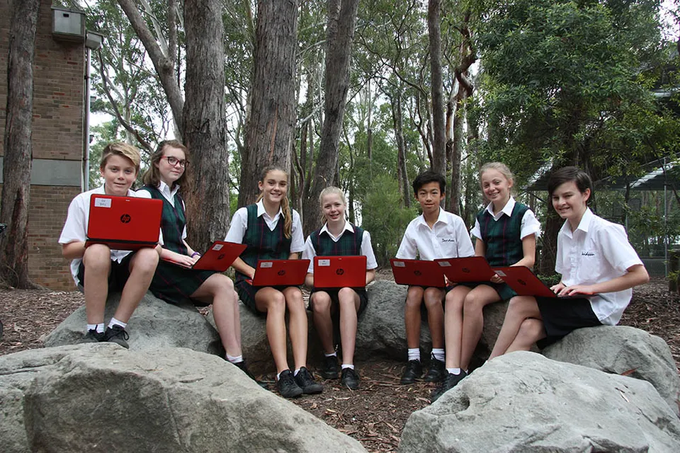 Studenti della Davidson High School in divisa scolastica sono seduti su delle rocce in un ambiente boschivo.