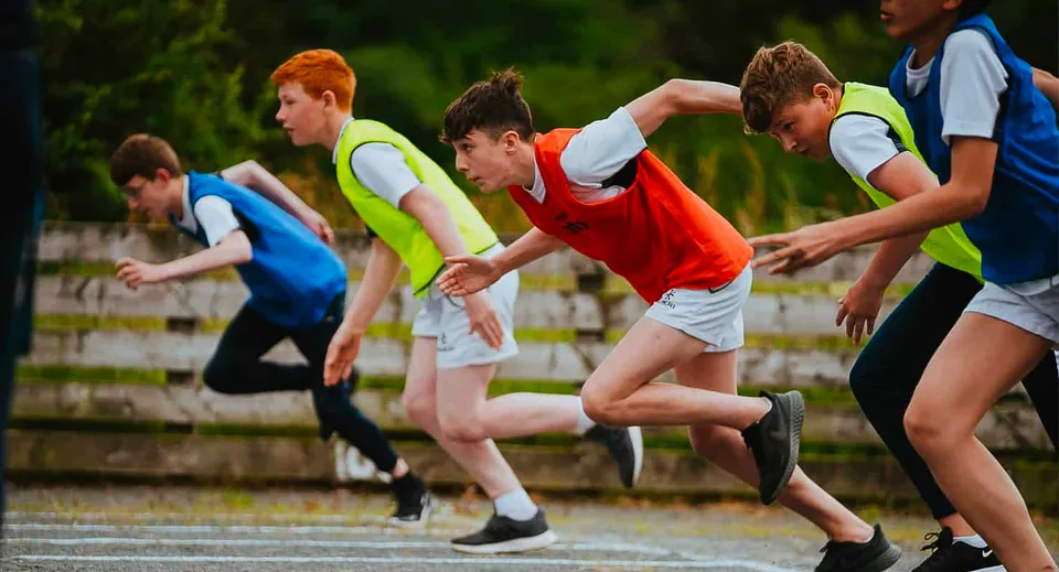 Un gruppo di giovani atleti corre sulla pista di atletica all'interno del campus della Royal School Dungannon.