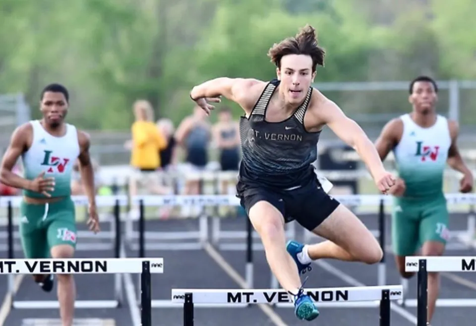 Un atleta della Mt. Vernon High School salta un ostacolo durante una gara sulla pista di atletica.