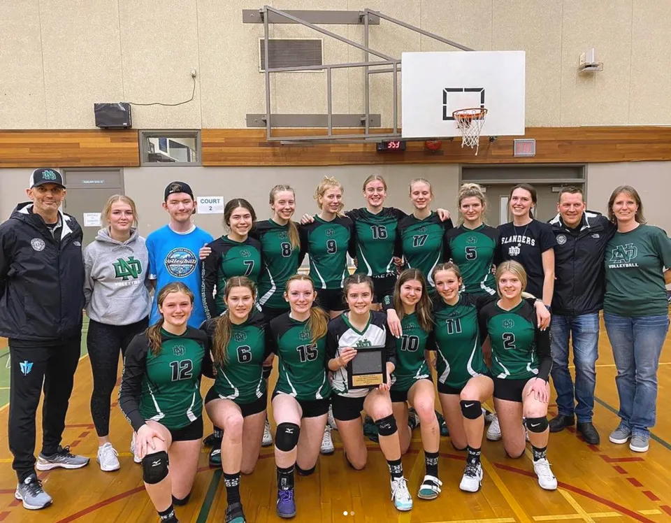 Un gruppo di studenti della Nanaimo District Secondary School in posa in palestra davanti a un canestro da basket.