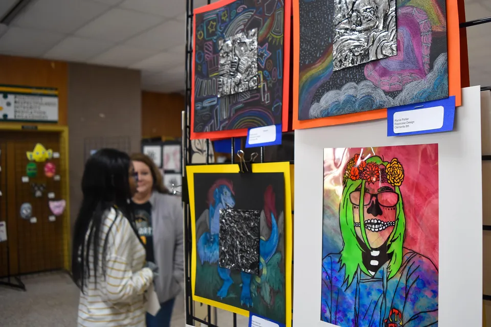 Un corridoio con opere d'arte colorate sulle pareti nel campus della Prince George Secondary School con una persona in primo piano.