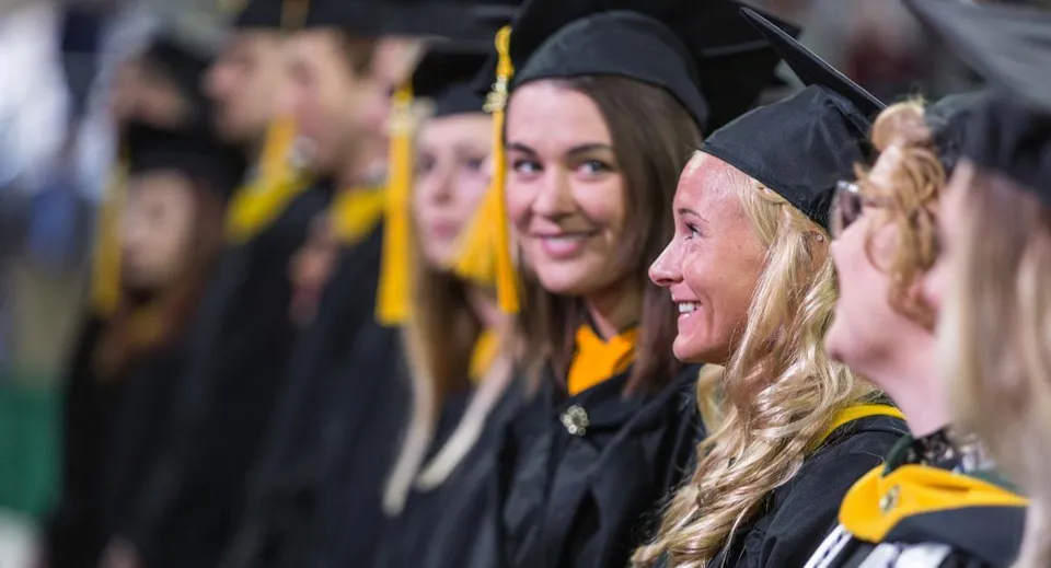 Un gruppo di diplomati in toga e tocco neri è riunito alla cerimonia di diploma del Guelph Collegiate Vocational Institute.