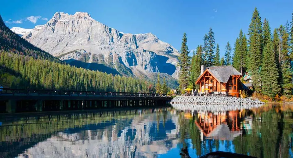 Un pittoresco paesaggio montano con lago e casa in legno si riflette nell'acqua calma senza alcun riferimento alla Gloucester High School.