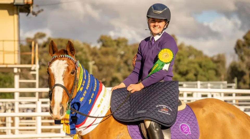 Una persona in uniforme viola cavalca un cavallo decorato a festa nei terreni del Coffs Harbour Senior College.