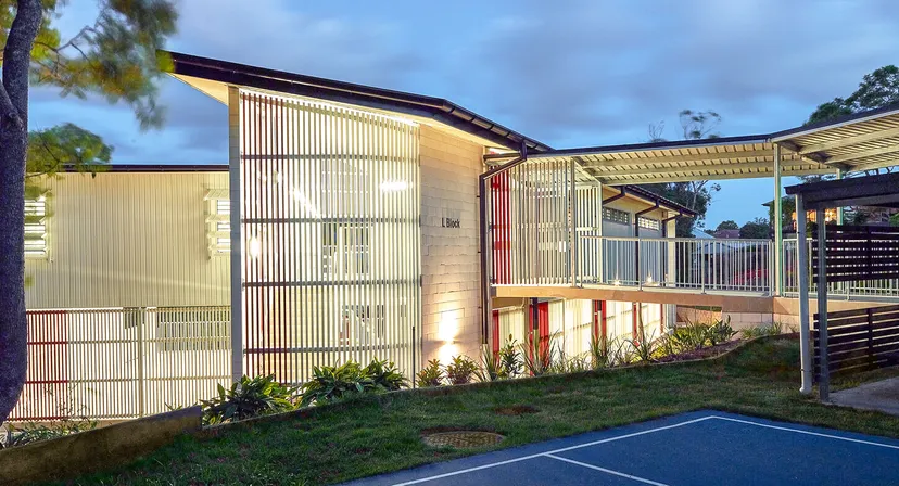 L'edificio moderno a più piani della Mount Gravatt State High School con una facciata in metallo e un'area verde in primo piano.