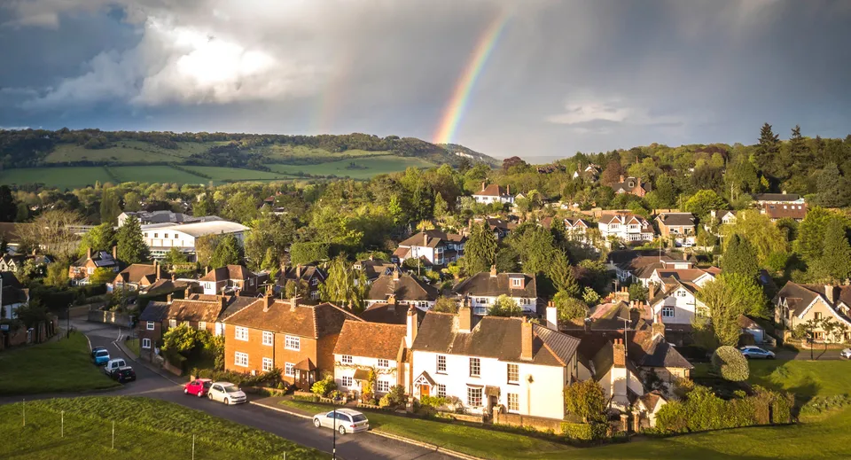 Un paesaggio pittoresco con un arcobaleno sopra un villaggio nei terreni di Hurtwood House.