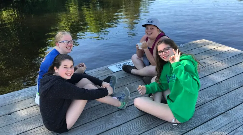 Un gruppo di giovani donne è seduto su un pontile di legno al lago nel terreno della Huntsville High School.