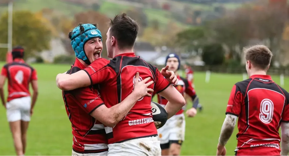 Un gruppo di giocatori di rugby della Giggleswick School festeggia su un campo da gioco.