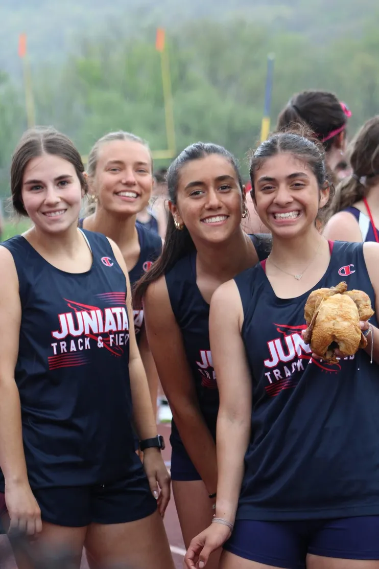 Quattro studentesse sorridenti in divisa della squadra di atletica di una high school americana