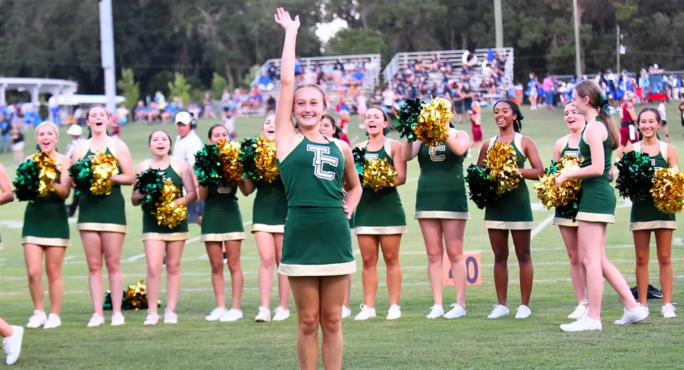 Cheerleader in divise verdi con pompon dorati sul campo sportivo della Trinity Catholic High School.