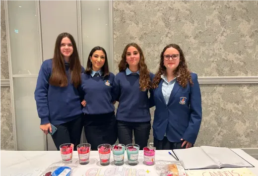 Vier Schülerinnen in Uniform hinter einem Stand mit selbst gemachten Kerzen in Irland