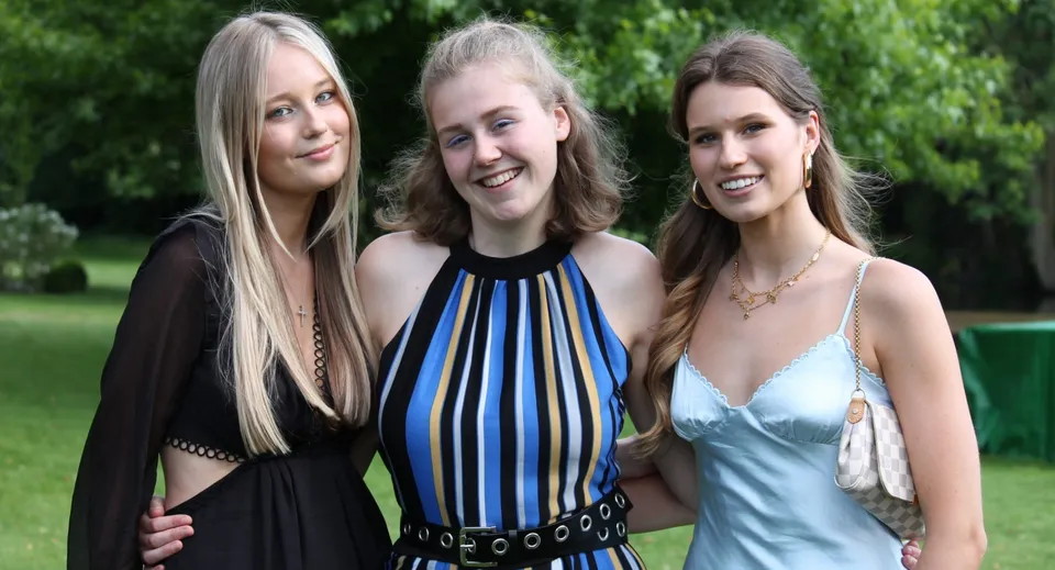 Tre studentesse con lunghi capelli biondi si trovano insieme in un'area verde all'aperto nei terreni della Queenswood School.