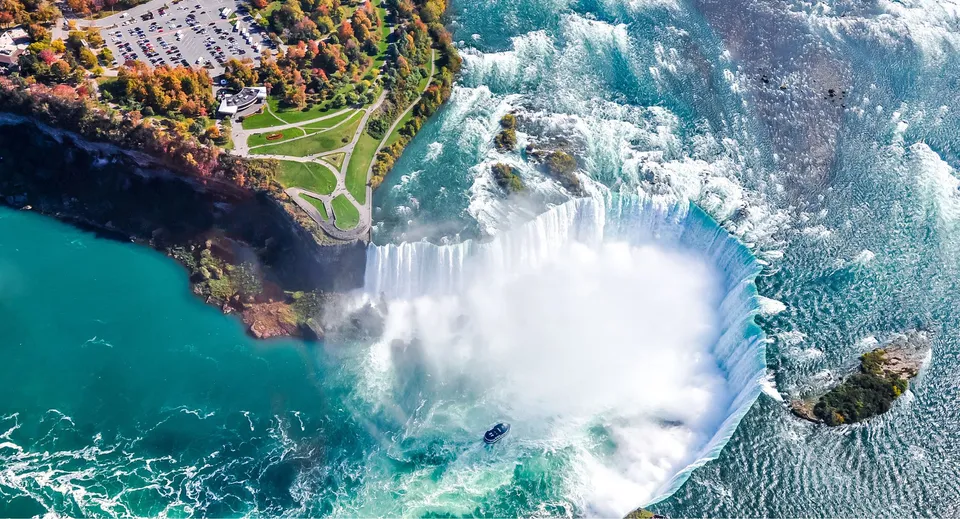 Una cascata scorre su una roccia davanti a un lago con fogliame autunnale nel campus della Queen Margaret’s School.