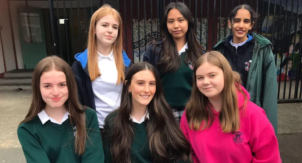 Un gruppo di studentesse si trova davanti a un edificio con un cancello in metallo nel campus della St. Mary's Secondary School a Charleville.