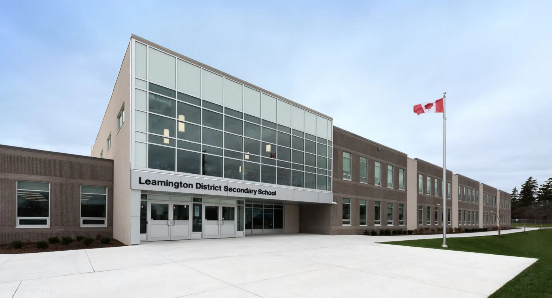 L'edificio scolastico moderno della Leamington District Secondary School con la bandiera canadese e l'area esterna curata.