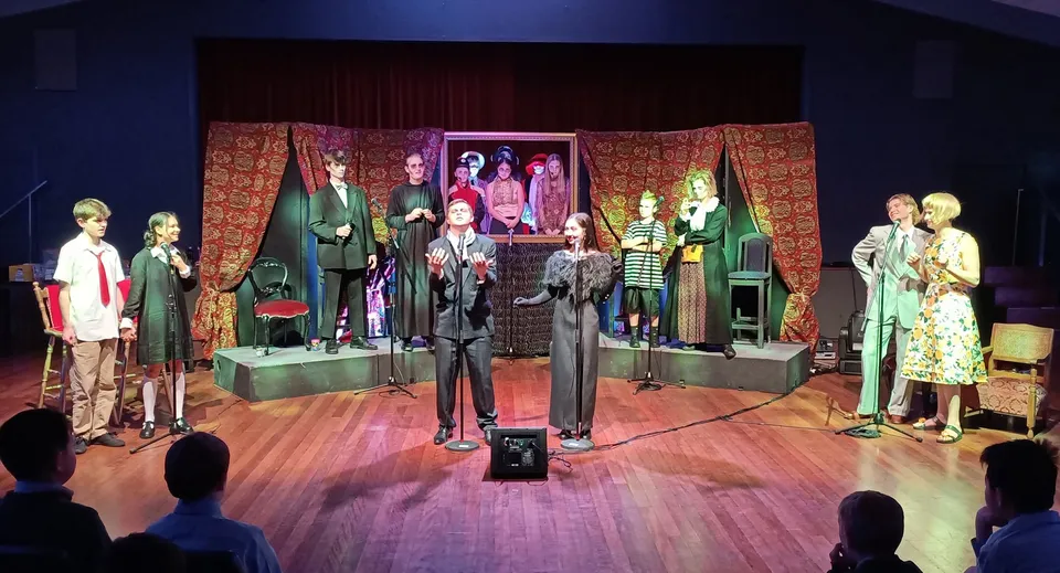 Sul palco del Scots College sono visibili manichini con abiti colorati di ispirazione vintage davanti a una tenda a motivi e ad opere d'arte.
