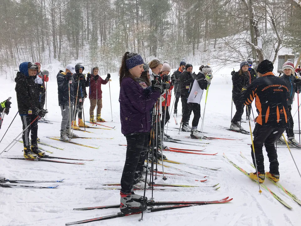 Un gruppo di studenti e studentesse della Orillia Secondary School sugli sci in un bosco innevato.