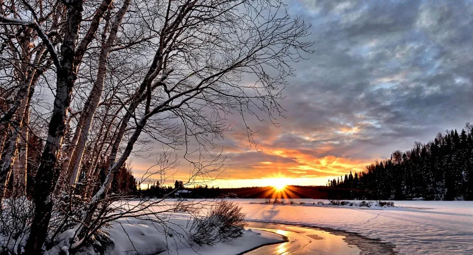 Paesaggio invernale con un lago ghiacciato e alberi innevati al tramonto vicino alla Vimy Ridge Academy.
