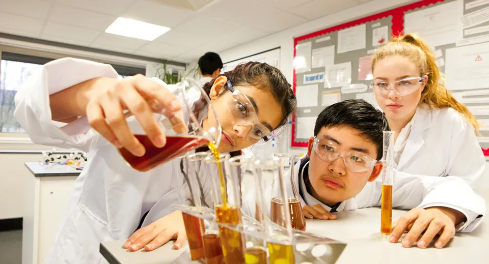 Tre studenti del National Mathematics & Science College lavorano insieme in un laboratorio a esperimenti scientifici.