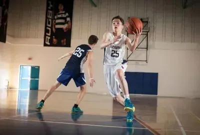 Dos jugadores de baloncesto de Kells Academy luchan por el balón en la cancha.