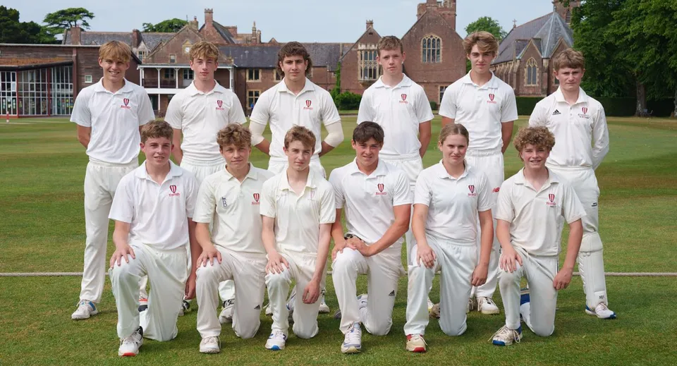 Un gruppo di studenti in divisa da cricket posa su un campo erboso davanti a un edificio storico nel campus del Bosworth Independent College.