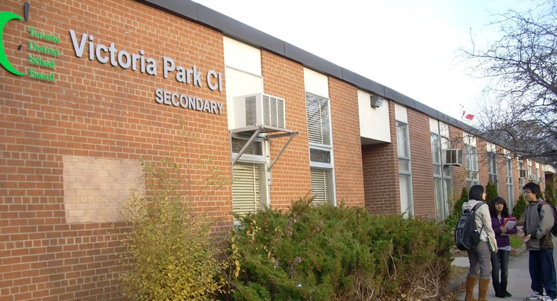 Tre studenti parlano davanti all'edificio in mattoni del Victoria Park Collegiate Institute.
