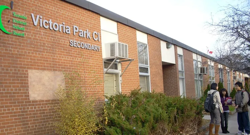 Tre studenti parlano davanti all'edificio in mattoni del Victoria Park Collegiate Institute.