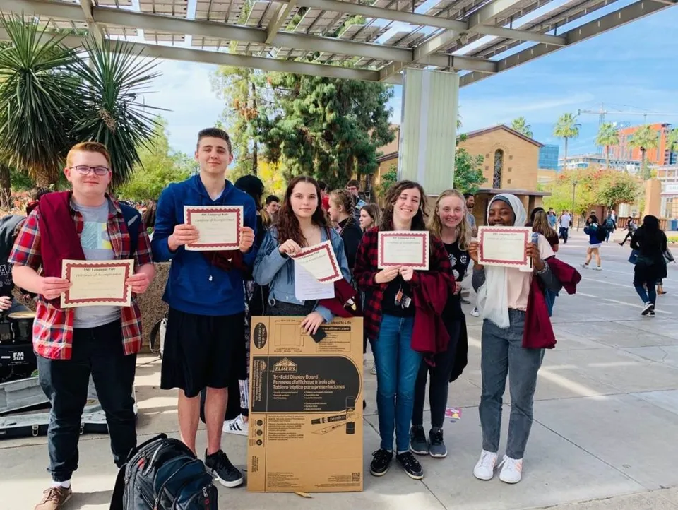 Gli studenti del Higley Unified School District alzano dei diplomi all'aperto.