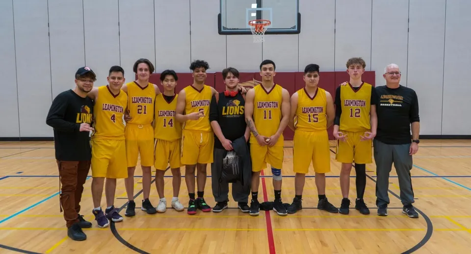 Un gruppo di giovani cestiste e cestisti si trova insieme sul campo da basket del Greater Essex County District School Board.