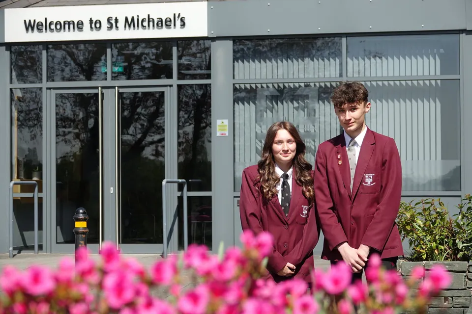 Due studenti in divisa scolastica sono in piedi davanti all'ingresso della St. Michael's School.