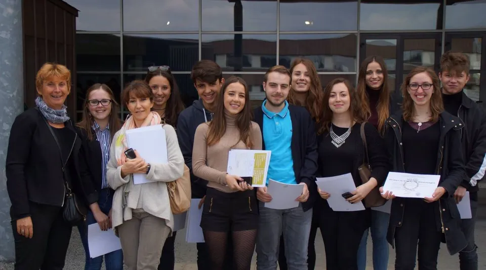 Un gruppo di studenti sta davanti all'edificio di vetro nel campus del Lycée Jean Brito e tiene in mano dei fogli.