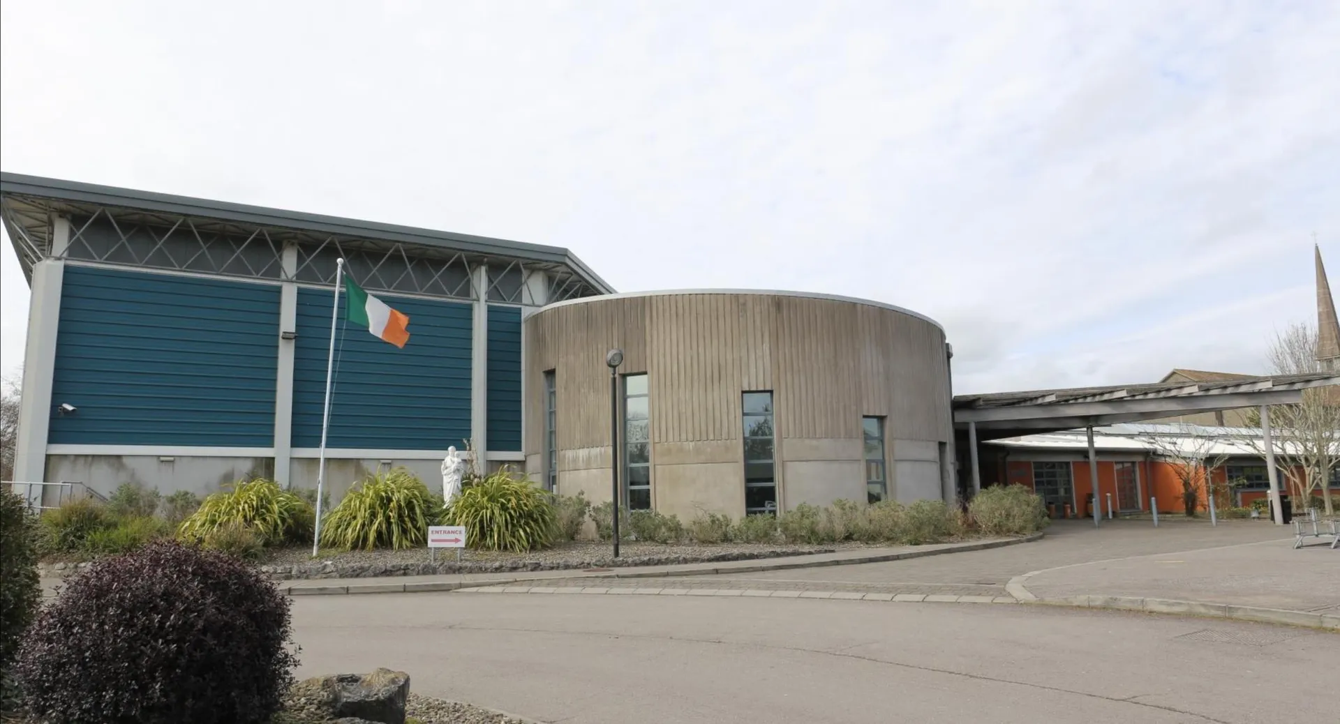 L'edificio moderno a più piani della Ursuline Secondary School a Cork, con un'architettura cilindrica curva, si trova davanti a un'area pavimentata.
