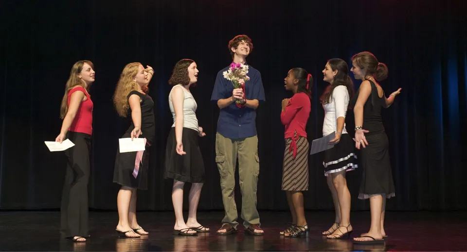 Studenti della Lester B. Pearson Catholic High School recitano su un palco teatrale davanti a un sipario nero.