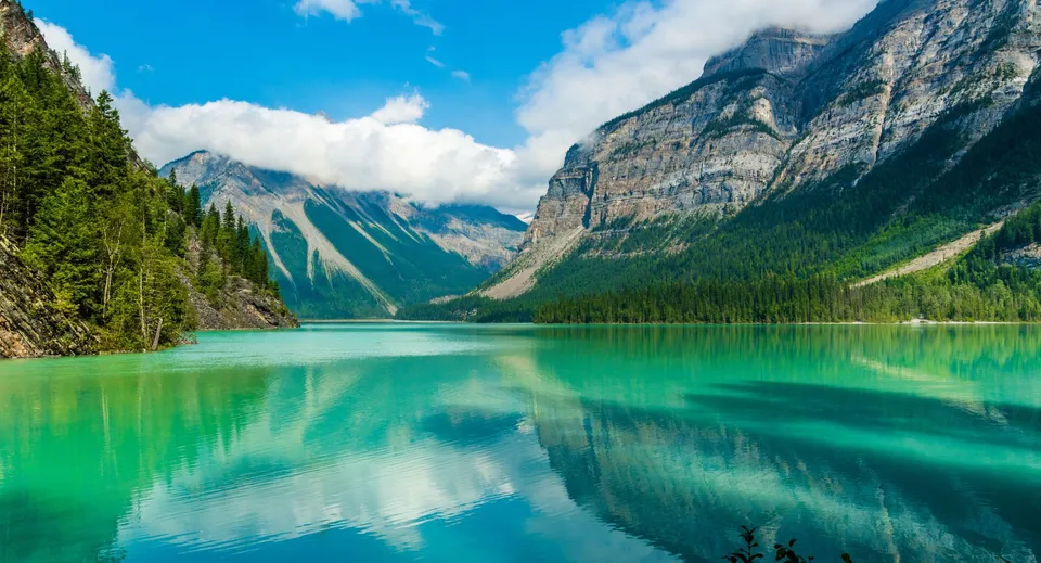 Un tranquillo lago turchese con montagne innevate e foreste sempreverdi nelle vicinanze della John F. Kennedy High School.