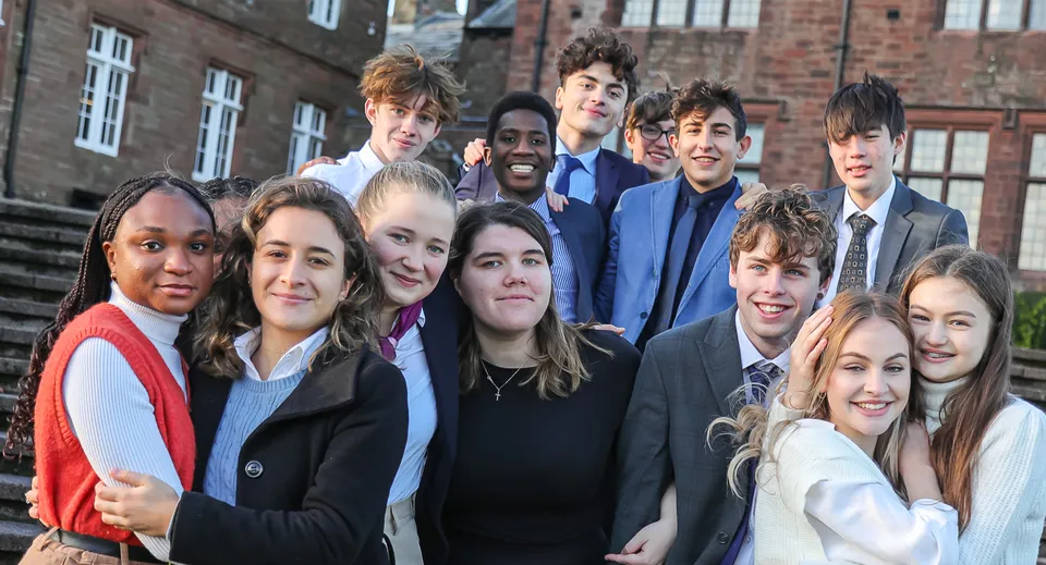 Un gruppo di studenti sorride davanti a un edificio in mattoni della St. Bees School.