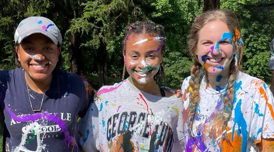 Tre studenti con colori vivaci sul viso e sui vestiti si trovano nel campus della Asheville School.
