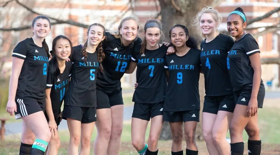 Un gruppo di giovani atlete della Miller School of Albemarle posa insieme all'aperto davanti ad alberi ed edifici.