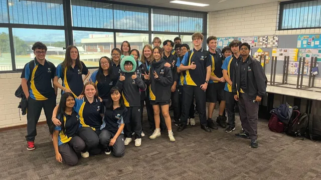 Clase de alumnos con uniforme escolar azul y amarillo posando en un aula