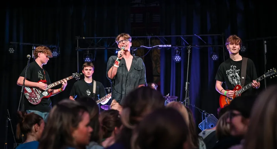 Una rock band della Sherborne School si esibisce sul palco davanti a un pubblico entusiasta.