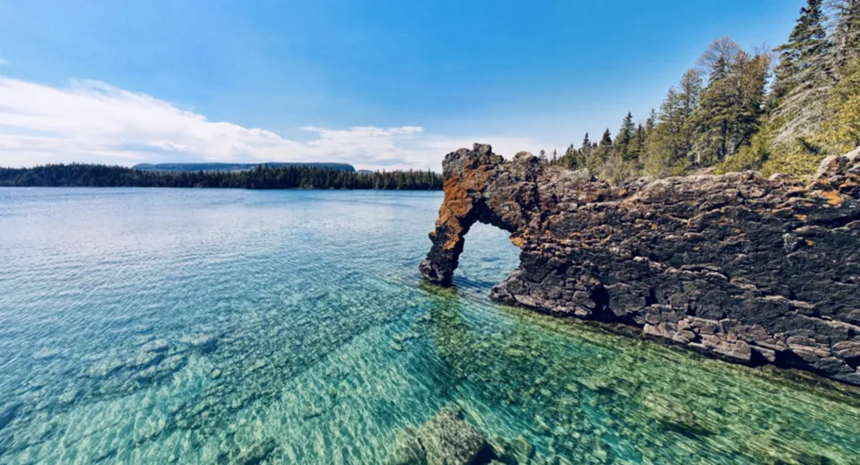 Una formazione rocciosa ad arco si erge in un lago limpido nel terreno della H.B. Beal Secondary School.