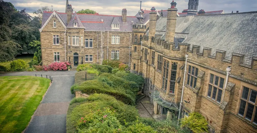 L'edificio principale in stile medievale della Rydal Penrhos School circondato da vegetazione verde e da un sentiero sinuoso.