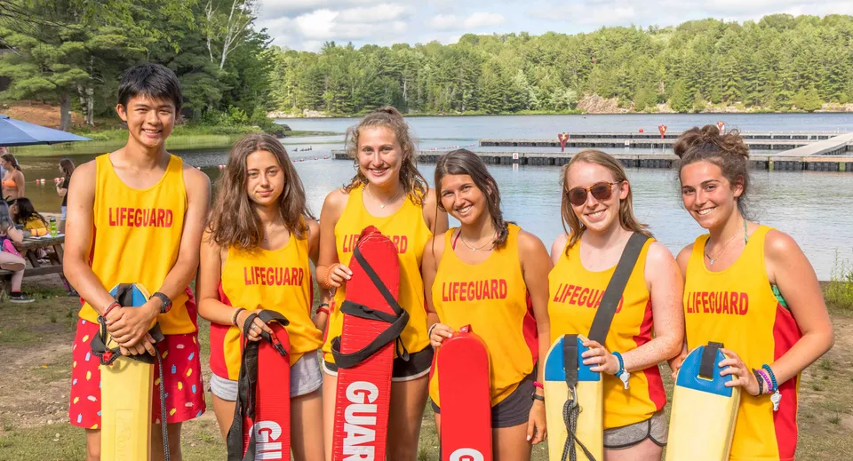 Un gruppo di bagnini si trova al lago nel campus della Kedron State High School davanti ad alberi verdi.