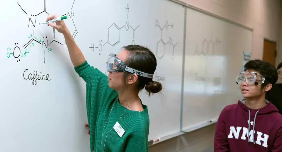 Una studentessa della Northfield Mount Hermon disegna una formula chimica su una lavagna bianca durante la lezione.