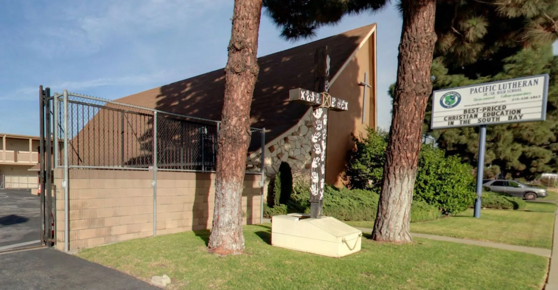 L'edificio moderno della Pacific Lutheran High School con un tetto triangolare si trova in un'area erbosa con alte palme.