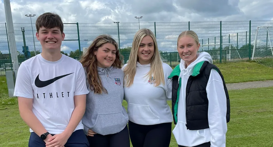 Quattro studenti e studentesse si trovano sul campo sportivo della Currie Community High School.