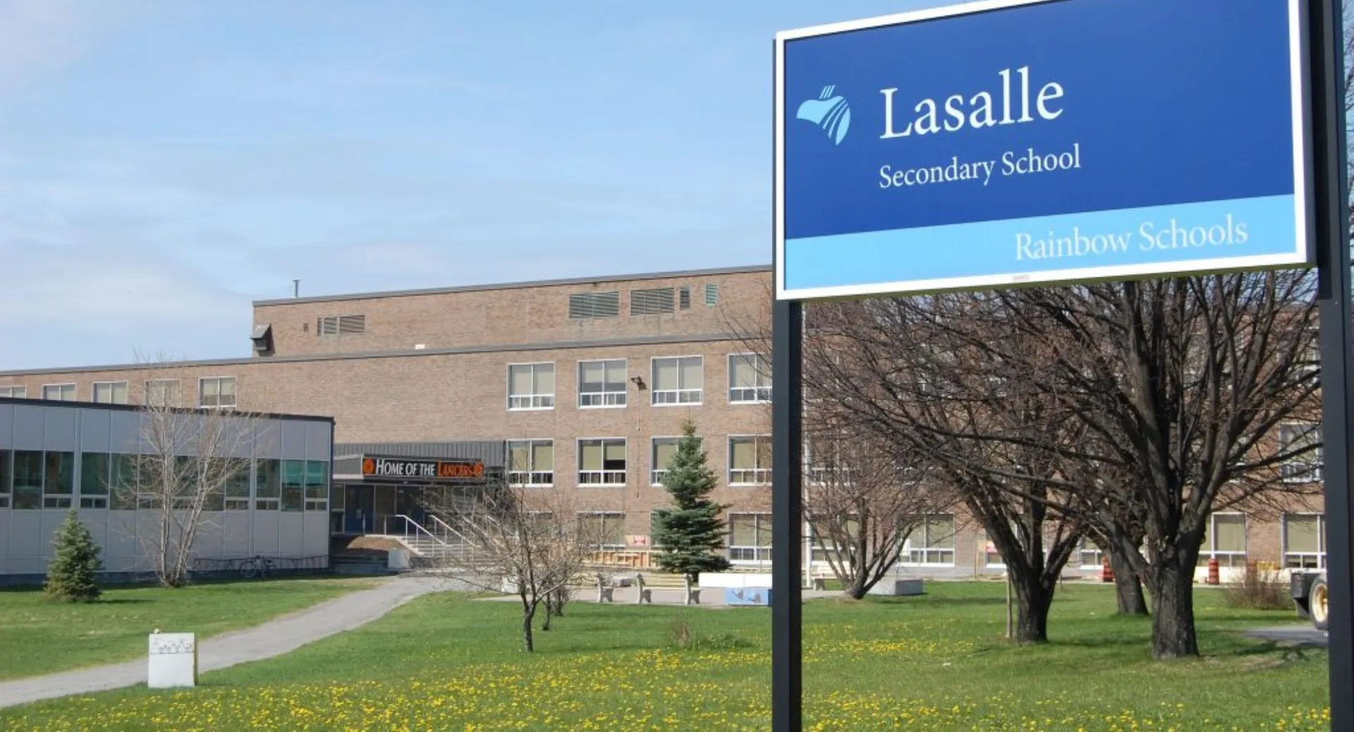 L'edificio della La Salle Secondary School con il nome e il logo della scuola è circondato da alberi e da un prato.